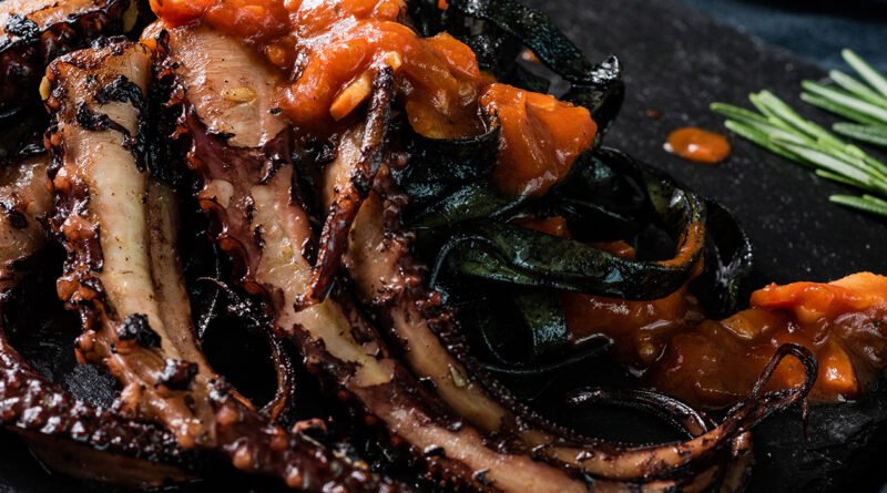 Pulpo a la plancha sobre pasta negra y tomate frito con ajo